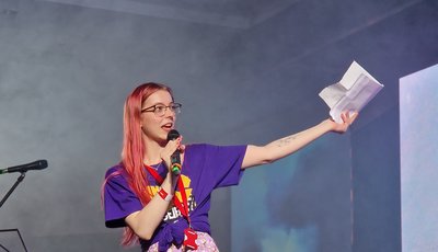 Bea Hulme, the Methodist Youth President, stands alone on a stage presenting to a crowd.