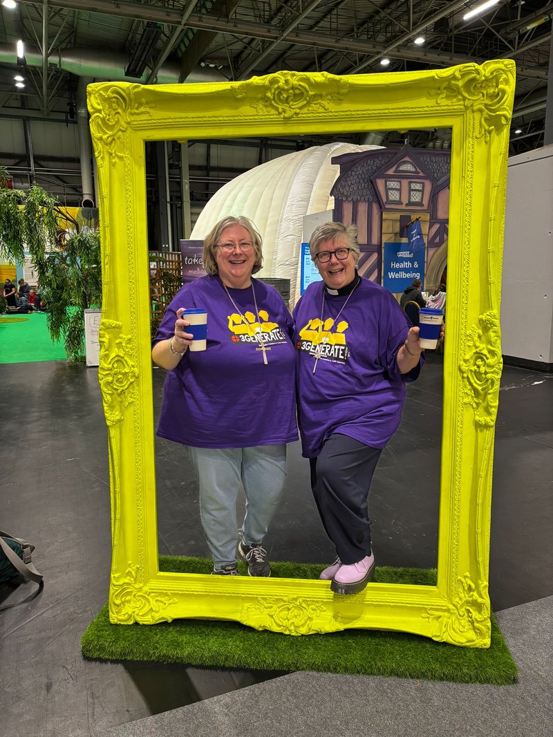 Two women, the President and Vice-President of the Methodist Conference, pose inside a yellow picture frame