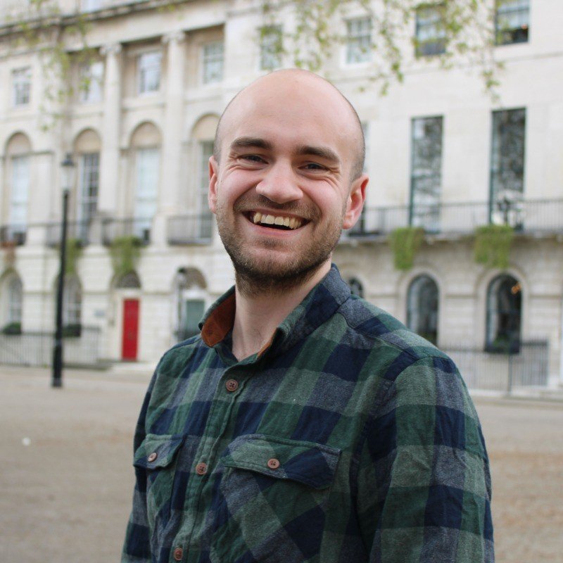 Headshot of Cameron Lee-Hume in a checked green shirt