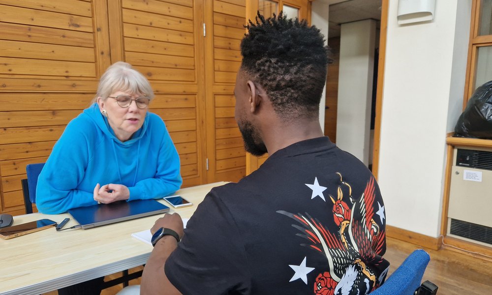 A volunteer in discission with a migrant at a table