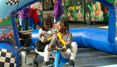 two young children riding on carts around an inflatable race track