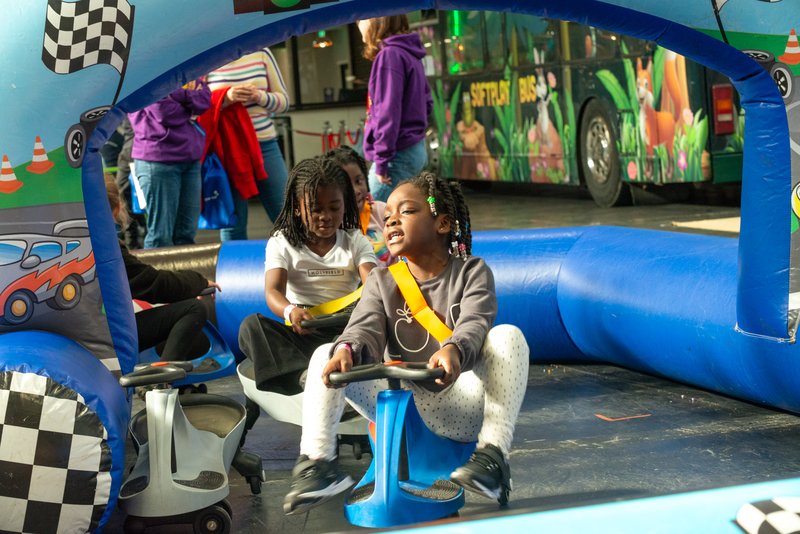 two young children riding on carts around an inflatable race track