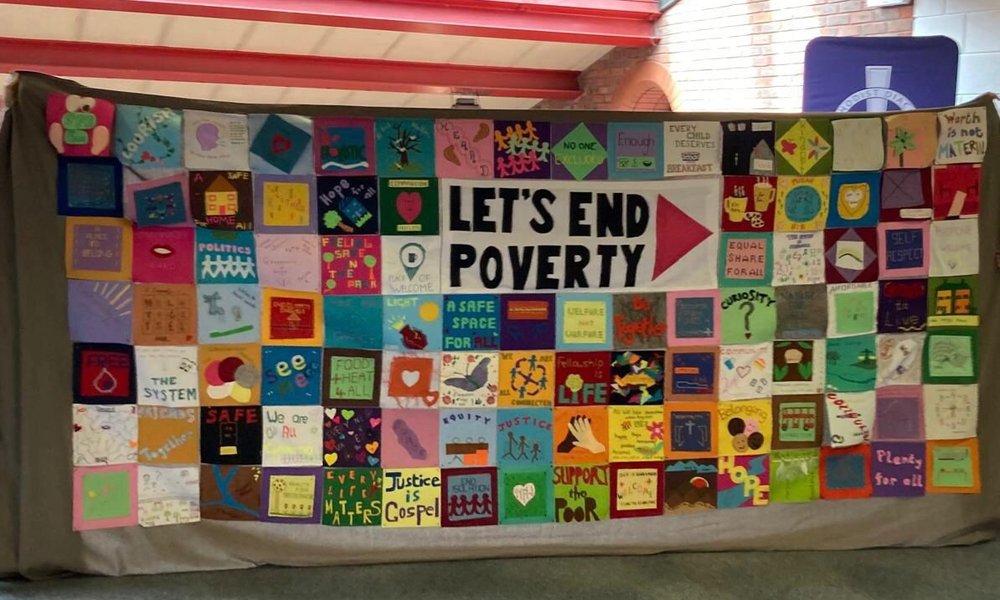 A banner made of stitched panels illustrated with words to identify how we can end poverty