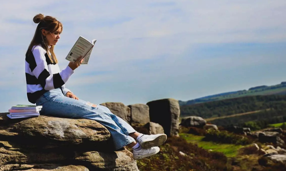 Student reading a book on a hill
