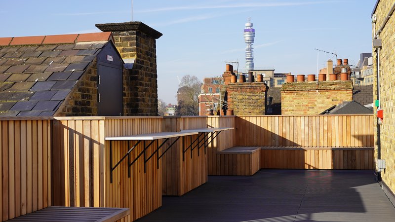 Wood‑clad rooftop terrace at Methodist Church House with the BT Tower visible beyond nearby chimney pots.