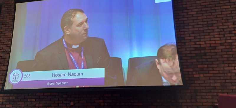 Image of the big screen in the meeting hall, showing Archbishop Hosam Naoum from Jerusalem, as he addresses General Synod in July 2025