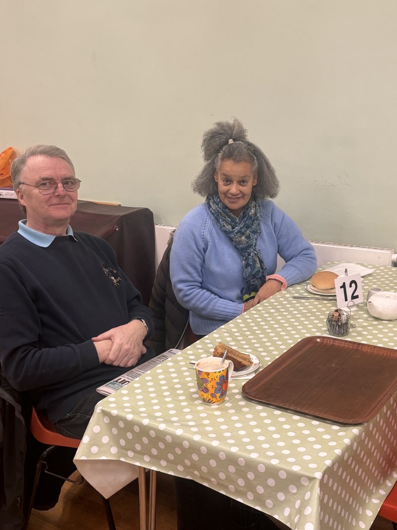 A man and woman sit at a cafe table at the Llandudno Warm Space