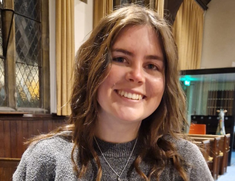 A woman standing in a church wearing a grey top