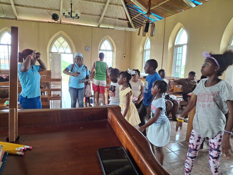 children raise hands and smile inside a well lit large wooden church