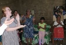 Dark room with group of young women clapping in worship