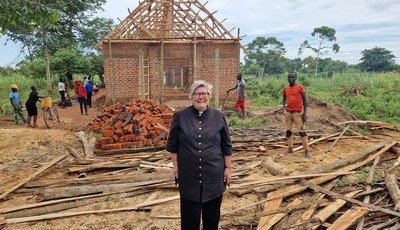 woman stand infront of a brick house with exposed wooden roof framework