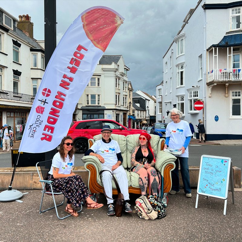 Three people in Sidmoth sitting on a sofa with one standing next to them and a Methodist banner