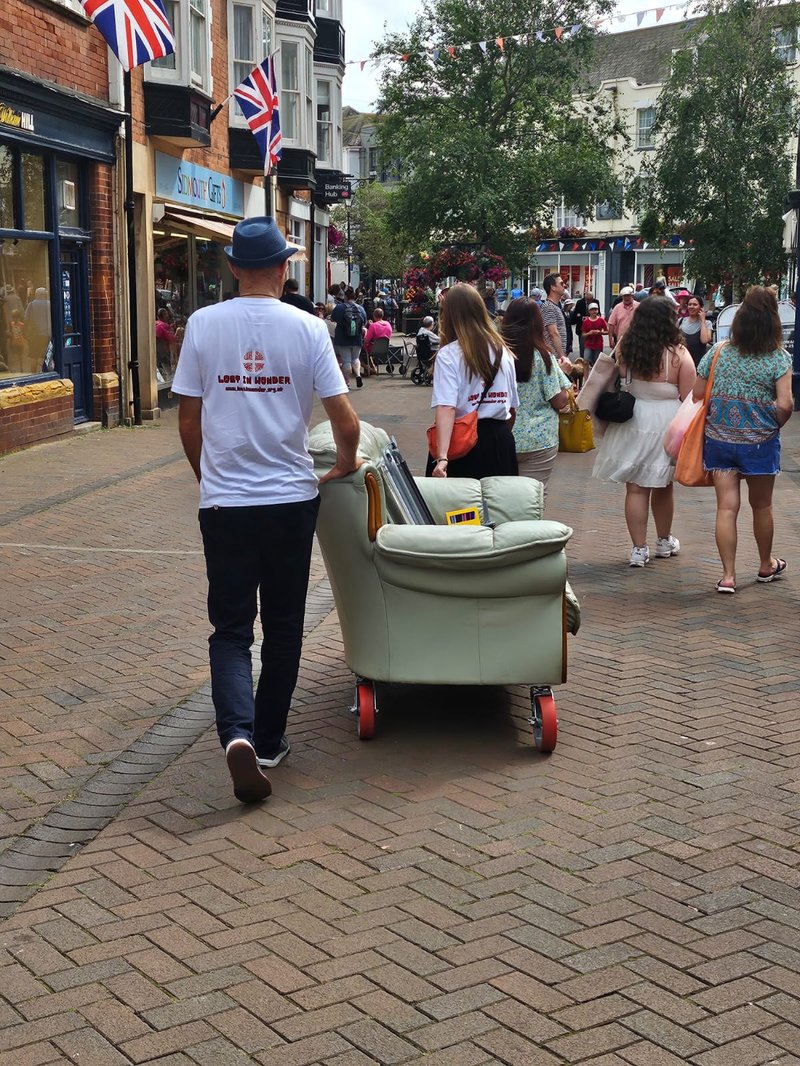 A sofa being pushed through a town centre