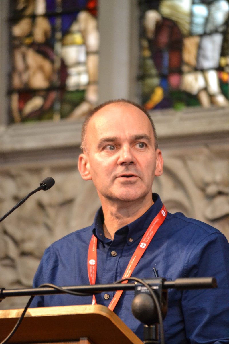 Stephen Skuce in a blue short speaking into a microphone