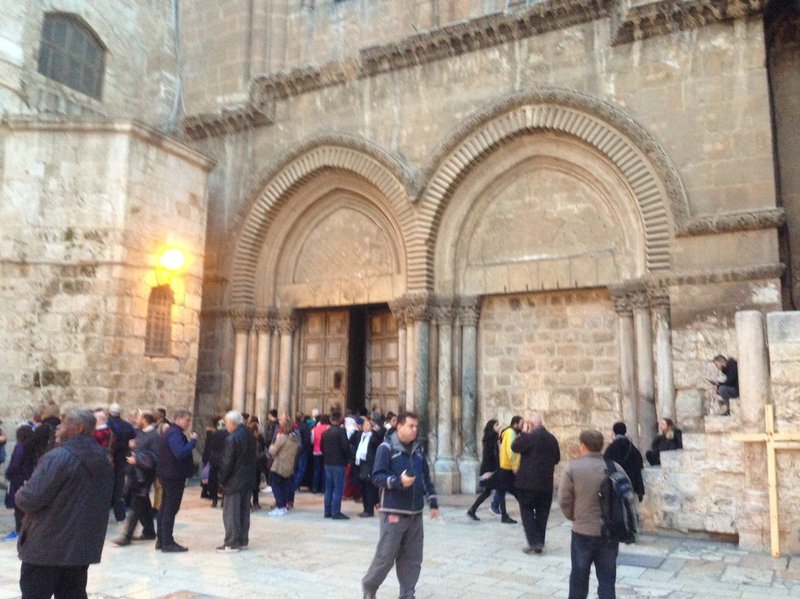People walking outside old stone church entrance, Jerusalem