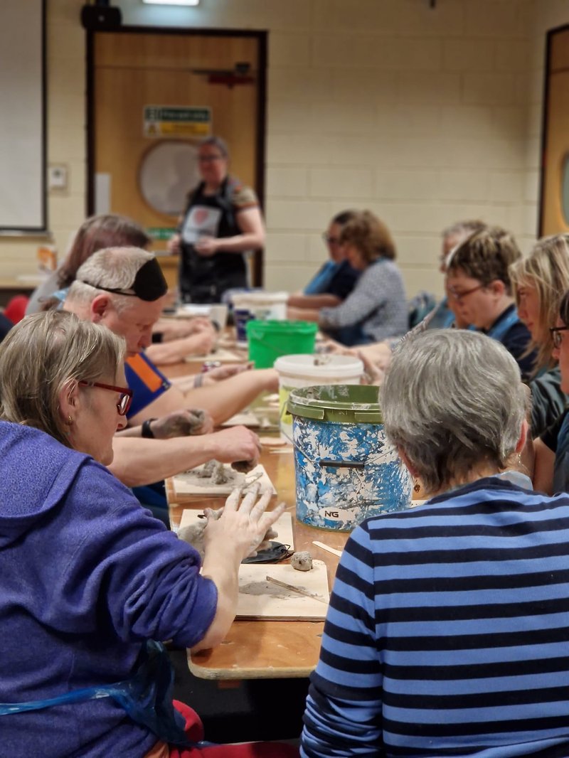 A group of people at tables crafting with clay at the Wholehearted Conference