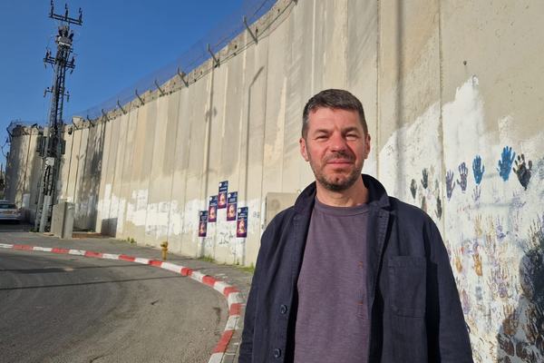 Mark Slaney stands in front of a security wall in Jerusalem