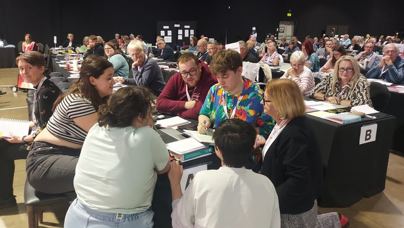 Young people gathered in conversation around a desk at the Methodist Conference