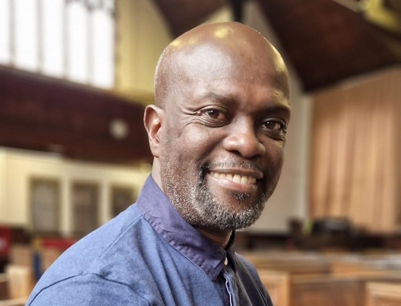 A man in a blue top sitting in a church