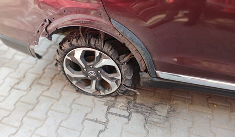 Rear right wheel of red car with significant damage and a blown out tyre