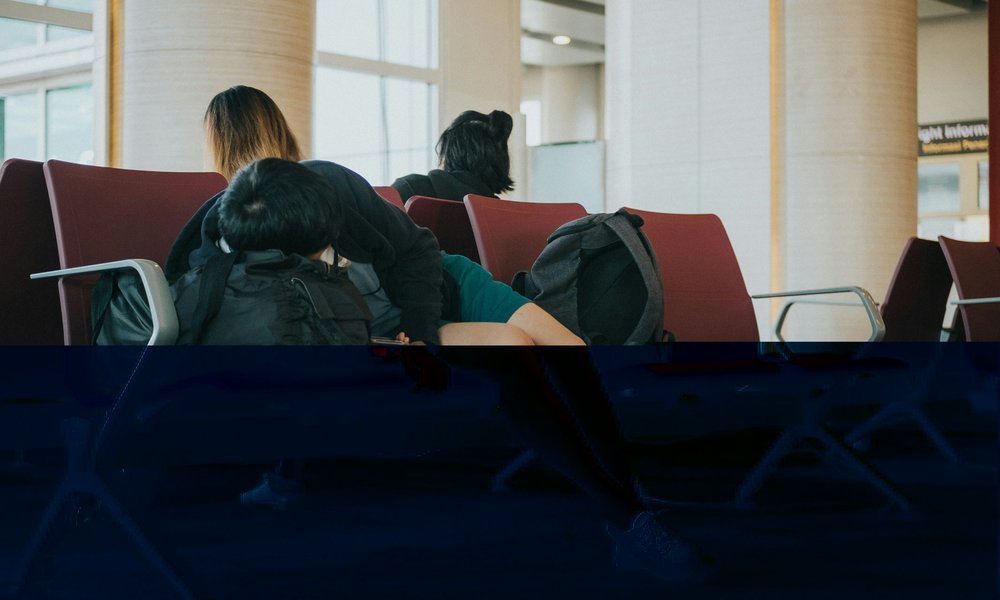 Someone trying to sleep on a bench in a railway station waiting room