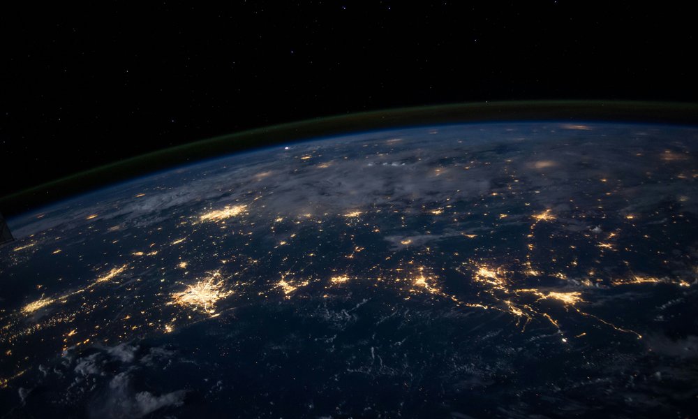 A photo of the globe from above at nighttime with rivers of light crossing the surface from cities
