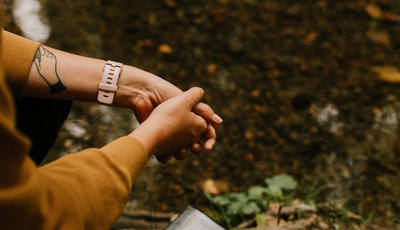 A view looking down on someone's hands held together as they prayer, outside the in forest.