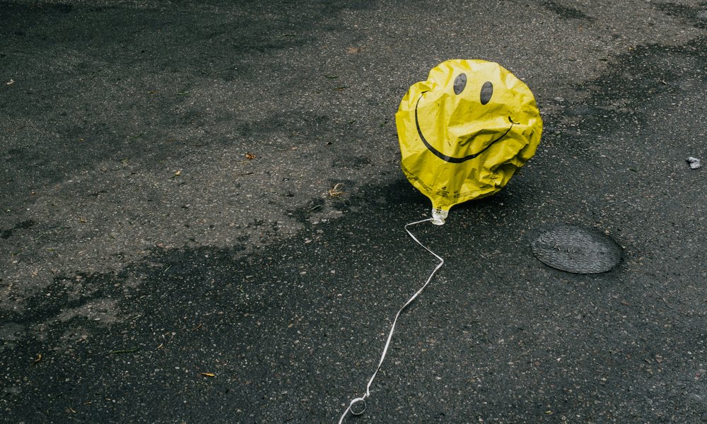 Photo: A deflated yellow with a balloon on it lies on the road next to cars