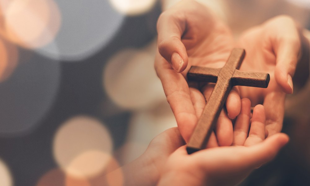 hands holding a small wooden cross