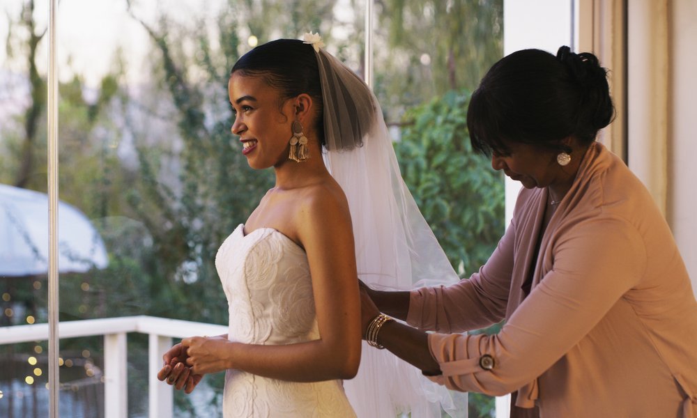 A bride is helped into her gown by another woman